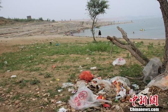 图为岗南水库大坝内游泳的人群和被丢弃的垃圾。 王天译 摄