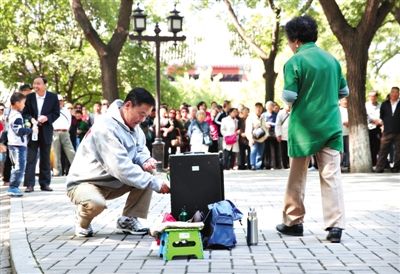 昨日，在北海公园一男子在调节扩音器，一女士手持话筒准备开唱。今年9月15日，北海和景山公园推出“降噪令”。 本版图片/新京报记者 尹亚飞 摄